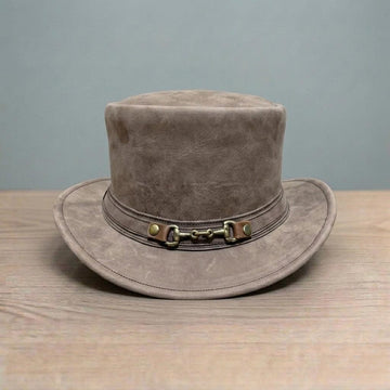 May include: A brown top hat with a wide brim. The hat has a leather band with a metal buckle detail. The hat is made of a soft, textured material and sits on a wooden surface.