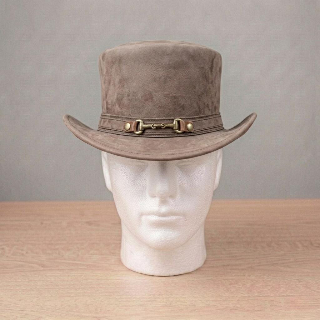 May include: A brown suede top hat with a wide brim and a decorative band featuring a metal buckle. The hat is displayed on a white mannequin head against a neutral background. The hat's colour is a muted brown.
